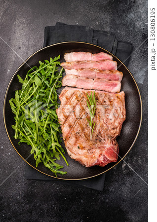 BBQ grilled pork tender steak, neck meat, on plate with salad. black background. top view BBQ grilled pork tender steak, neck meat, on plate with salad. black background. top view 130806195