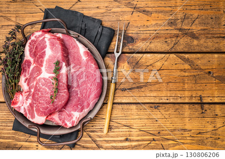 Uncooked pork tender steak, raw sliced neck meat with thyme. wooden background. top view Uncooked pork tender steak, raw sliced neck meat with thyme. wooden background. top view 130806206