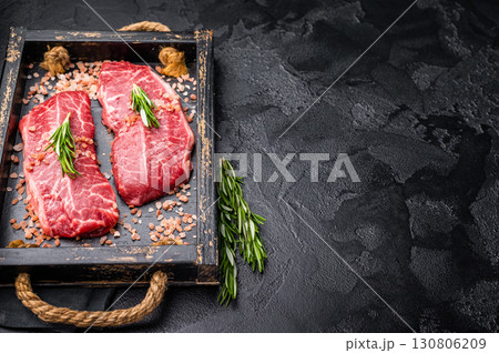 Raw Top blade steak, shoulder beef meat in wooden tray. black background. top view 130806209