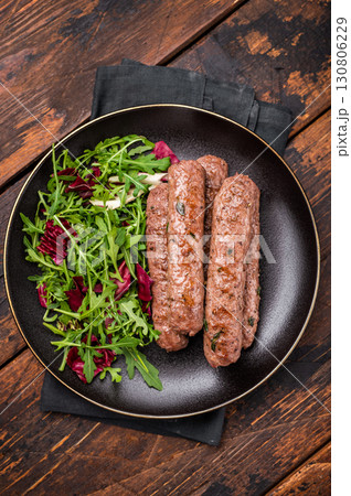 Roasted beef and lamb meat kebabs sausages on plate with salad. wooden background. top view 130806229