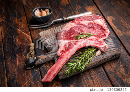 Raw Tomahawk beef steak, fresh black angus ribeye with bone on wooden board. wooden background. top view 130806235