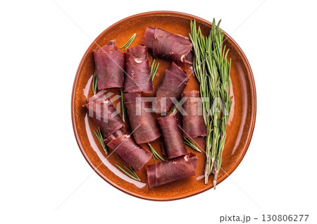 Typical dried spanish meat cecina, spanish beef jamon on plate with rosemary isolated on white background. top view Typical dried spanish meat cecina, spanish beef jamon on plate with rosemary isolated on white background. top view 130806277