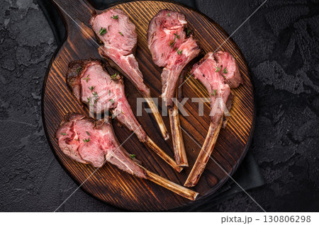 French roast lamb chops, mutton meat steaks on wooden board. black background. top view French roast lamb chops, mutton meat steaks on wooden board. black background. top view 130806298