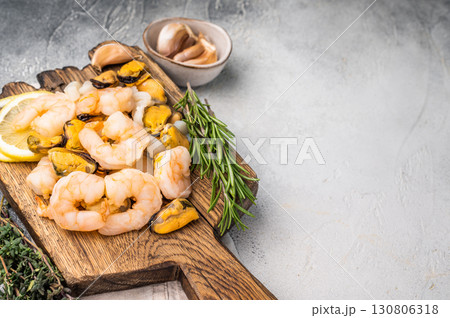 Fresh Seafood cocktail, raw Mix with Mussels, Clams, Prawns, Shrimps and squid on wooden board. white background. top view Fresh Seafood cocktail, raw Mix with Mussels, Clams, Prawns, Shrimps and squid on wooden board. white background. top view 130806318