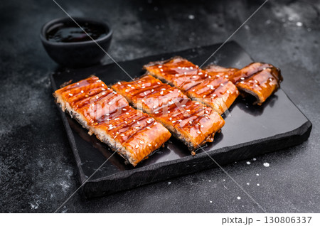 Unagi kabayaki eel, japanese grilled fish fillet with sauce. black background. top view Unagi kabayaki eel, japanese grilled fish fillet with sauce. black background. top view 130806337
