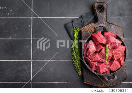 Diced Raw Ostrich meat, uncooked Game Meat in a skillet. black background. top view Diced Raw Ostrich meat, uncooked Game Meat in a skillet. black background. top view 130806354