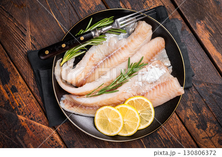 Organic Raw Haddock fish fillets, whitefish on a plate with herbs. wooden background. top view 130806372