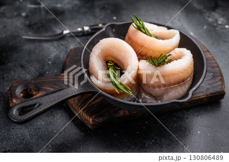 Ready for cooking Raw Pollock fish fillets in pan with herbs. black background. top view Ready for cooking Raw Pollock fish fillets in pan with herbs. black background. top view 130806489