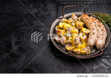 Currywurst sliced Sausages with curry sauce, wurst in steel plate. black background. top view Currywurst sliced Sausages with curry sauce, wurst in steel plate. black background. top view 130806522