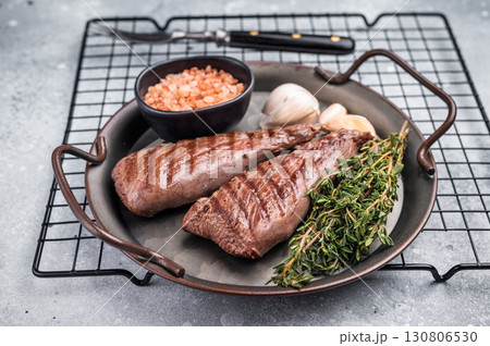 Grilled Mutton tenderloin fillet steak, lamb meat with herbs. grey background. top view Grilled Mutton tenderloin fillet steak, lamb meat with herbs. grey background. top view 130806530