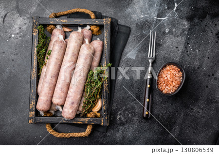 Raw Sausages with minced chicken and turkey meat with herbs in wooden tray. black background. top view Raw Sausages with minced chicken and turkey meat with herbs in wooden tray. black background. top view 130806539