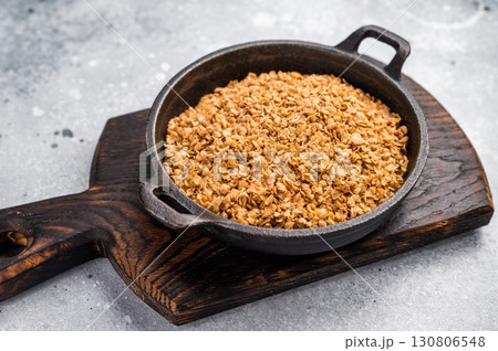 Raw buckwheat flakes in a skillet. grey background. top view Raw buckwheat flakes in a skillet. grey background. top view 130806548