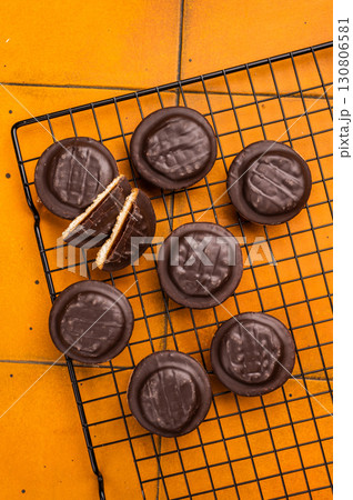 Fresh cooked Jaffa Cookies covered with chocolate and filled with jam on rack. orange background. top view Fresh cooked Jaffa Cookies covered with chocolate and filled with jam on rack. orange background. top view 130806581
