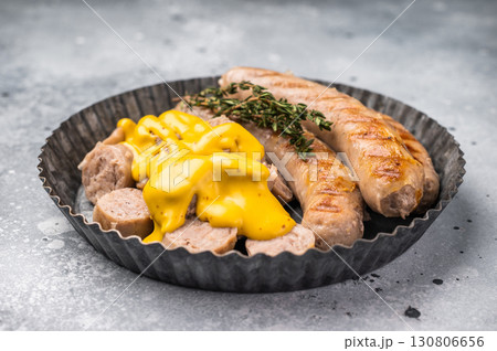 Grilled Bratwurst Sausages with cheese sauce in plate. grey background. top view Grilled Bratwurst Sausages with cheese sauce in plate. grey background. top view 130806656
