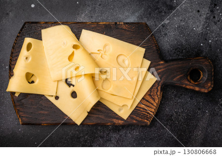 Swiss emmental cheese slices on wooden cutting board. black background. top view Swiss emmental cheese slices on wooden cutting board. black background. top view 130806668