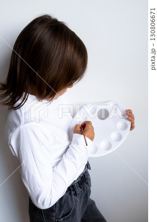 Young caucasian child painting with palette in white shirt Young caucasian child painting with palette in white shirt 130806671