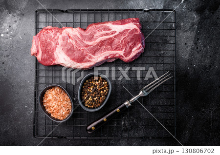Ready for cooking Chuck eye roll steak, fresh raw beef meat on a rack. black background. top view 130806702