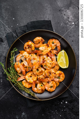 Grilled spicy Shrimps Prawns with garlic and lime in a plate. Black background. Top view Grilled spicy Shrimps Prawns with garlic and lime in a plate. Black background. Top view 130806725