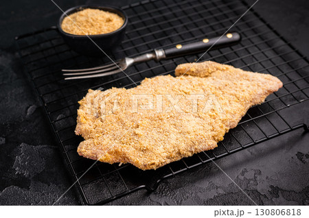 Raw breaded pork Schnitzel steak on a rack. black background. top view 130806818