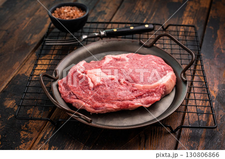 Prime Rib eye steak in a tray, raw dry aged beef meat on wooden background. top view 130806866