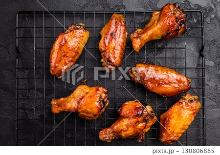 Mouthwatering BBQ chicken wings, coated in a rich sauce, perfect for finger-licking appetizers at any gathering. black background. top view 130806885