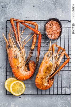 Close up of beautifully grilled rosenbergii prawn, showcasing its smoky glaze and appetizing texture. grey background. top view Close up of beautifully grilled rosenbergii prawn, showcasing its smoky glaze and appetizing texture. grey background. top view 130806887