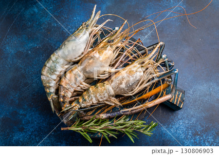 Uncooked rosenbergii fresh water shrimp ready for preparation, perfect for chefs looking to create exquisite seafood dishes. blue background. top view Uncooked rosenbergii fresh water shrimp ready for preparation, perfect for chefs looking to create exquisite seafood dishes. blue background. top view 130806903