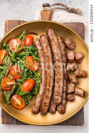 Close up of perfectly charred grilled sausage with salad, ideal for adding flavor to your favorite dishes or sandwiches. white background. top view Close up of perfectly charred grilled sausage with salad, ideal for adding flavor to your favorite dishes or sandwiches. white background. top view 130806914