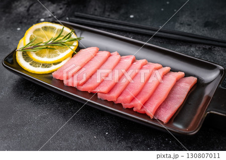 Premium quality tuna sashimi, expertly cut for maximum tenderness and taste, perfect for sushi enthusiasts. black background. top view Premium quality tuna sashimi, expertly cut for maximum tenderness and taste, perfect for sushi enthusiasts. black background. top view 130807011