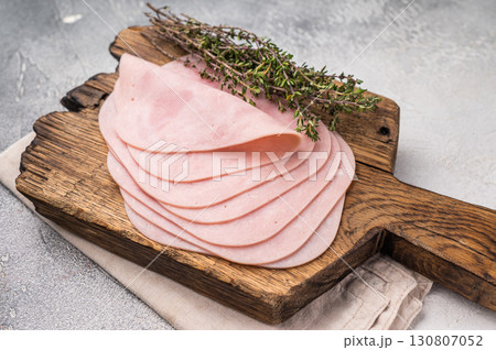 Delicious slices of cured ham on a wooden platter, ideal for entertaining and adding flavor to your dishes. white background. top view Delicious slices of cured ham on a wooden platter, ideal for entertaining and adding flavor to your dishes. white background. top view 130807052