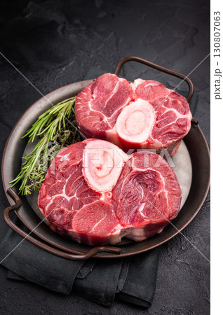 Freshly cross cut shank osso buco, ossobuco meat featuring succulent meat and bone marrow, waiting to elevate your cooking experience. black background. top view Freshly cross cut shank osso buco, ossobuco meat featuring succulent meat and bone marrow, waiting to elevate your cooking experience. black background. top view 130807063