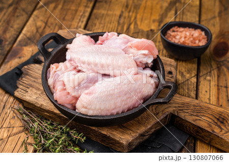 Juicy uncooked chicken wings, a versatile ingredient perfect for frying, baking, or grilling to perfection. wooden background. top view 130807066