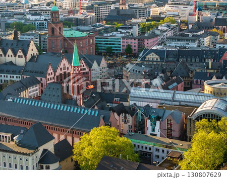 Aerial image of Frankfurt, Germany, featuring the Romer, St. Nicholas Church, colorful facades, modern buildings, and greenery in the foreground. 130807629