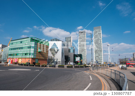 Contemporary London area with unique architecture, skyscrapers, Emirates Air Line cable cars, a red double decker bus, and clear blue skies. 130807787