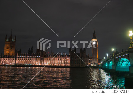 The Houses of Parliament and Big Ben glow against a dark sky, with the River Thames reflecting their lights. Westminster Bridge is visible to the right. 130807835