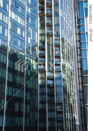 Urban scene featuring contemporary high rise buildings with glass facades, balconies, and reflections. Likely located in London, no landmarks visible. 130807940