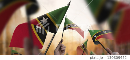 Saint Kitts and Nevis flags in their hands on a blurred urban background 130809452