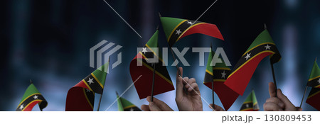 Saint Kitts and Nevis flags in their hands on a blurred urban background Saint Kitts and Nevis flags in their hands on a blurred urban background 130809453