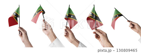 The Saint Kitts and Nevis flag in hand in different angles on a white background 130809465