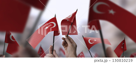 Turkey flags in their hands on a blurred urban background Turkey flags in their hands on a blurred urban background 130810219