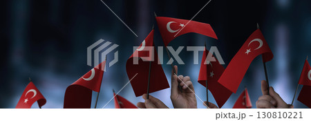 Turkey flags in their hands on a blurred urban background 130810221