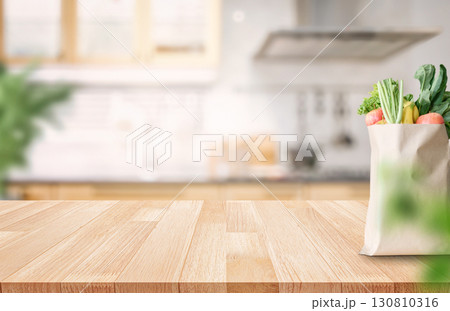 Fresh groceries in paper bag on wooden countertop with kitchen background 130810316