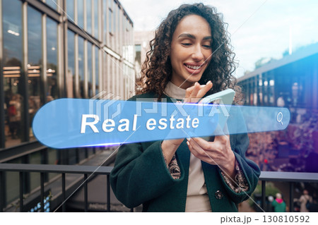 Young woman browsing real estate listings on smartphone at modern urban location during daytime Young woman browsing real estate listings on smartphone at modern urban location during daytime 130810592