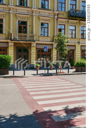 Street view of a colorful building with crosswalk and plants in a city setting during sunny weather Street view of a colorful building with crosswalk and plants in a city setting during sunny weather 130810593