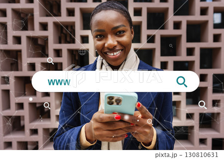 Smiling woman holding smartphone while searching online in urban setting 130810631
