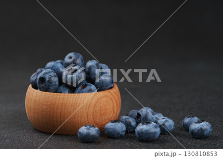 Fresh ripe blueberries in wooden bowl on dark gray stone background closeup macro healthy food 130810853