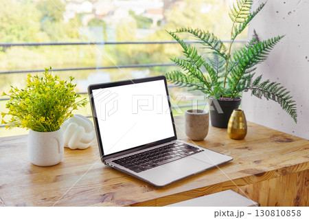Laptop computer with white screen on wooden desk on window background. Mockup, template, copy space 130810858