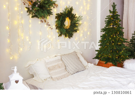 Christmas tree and wreath in bedroom, holiday decor and warm lighting during winter months 130810861