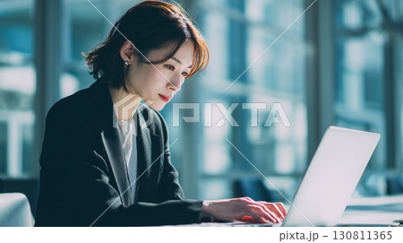 明るいオフィスで仕事に集中する若いビジネスウーマン 130811365