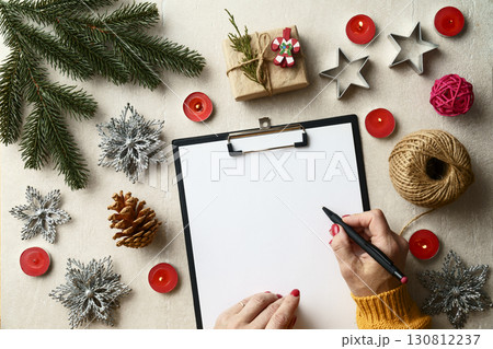 Woman writing a letter to Santa Claus at a festive table Woman writing a letter to Santa Claus at a festive table 130812237